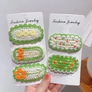 Detail of handmade crochet flower hair clips in green and orange knit textures