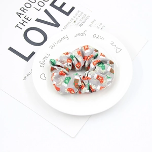 Close-up of a grey Christmas scrunchie with festive sock patterns on a white tray