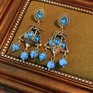 Detailed macro view of vintage gold chandelier earrings with blue stones and faux turquoise