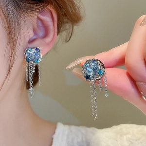 Détail de boucles d'oreilles en cristal bleu avec chaînes et design goutte d'eau