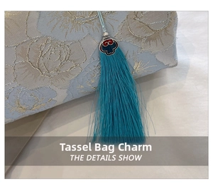 Detail of blue tassel charm with intricate metallic Chinese cloud pattern on bag