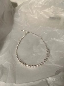 Detail view of pearl and silver bead拼接 necklace on white crumpled paper background