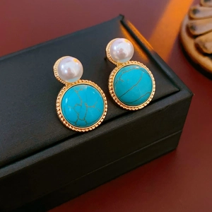 Vintage gold stud earrings featuring white pearls and green turquoise on a black gift box