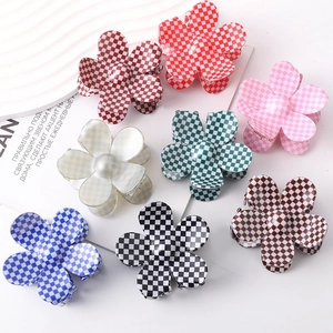 Flat lay of eight colorful flower-shaped checkerboard hair claws in various vibrant tones