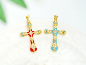 Detailed close-up of 18K gold-plated cross pendants with red and blue enamel and zircons