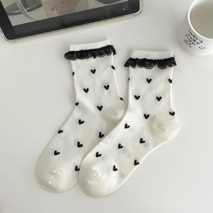 White crew socks with black heart pattern and lace trim in a minimalist setting