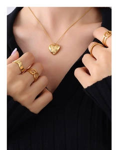 Detailed close-up of a sparkling gold heart pendant necklace on a black knit background