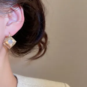 Elegant champagne diamond rhombus dangle earrings on model featuring a minimalist gold hook
