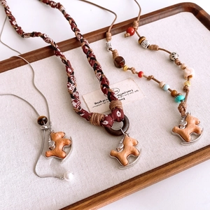 Detailed view of handcrafted wooden rocking horse pendants on diverse vintage ethnic necklaces