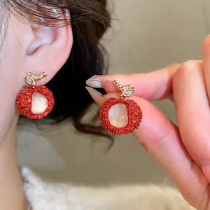 Zircon resin apple earrings with red textured finish and translucent core shown on ear