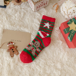 Close-up of fluffy Christmas coral fleece socks with ginger man embroidery and gift box