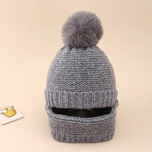 Detail of grey knitted baby winter hat set with large pompom and neck warmer protection