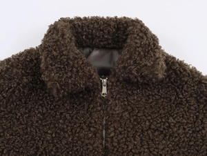 Detailed close-up of dark brown sherpa jacket collar with XS size label and metal zipper