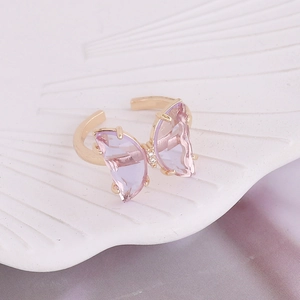 Macro detail of golden butterfly ring with faceted purple crystal on shell tray