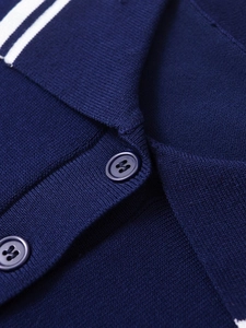 Détail d'un polo en tricot bleu marine avec bordure de col blanche et boutons texturés