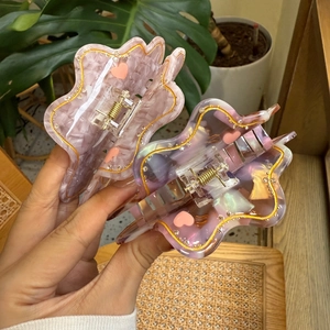 Detail of acetate hair claws featuring wave edges, heart patterns, and marble texture