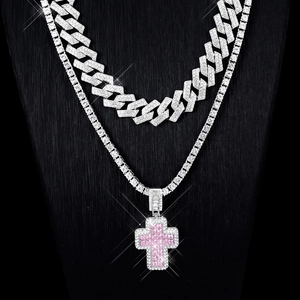 Detail of silver Cuban and tennis chains with a pink gemstone cross pendant on neck