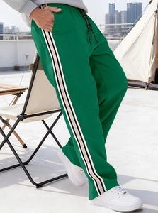 Detail view of green jogger pants with side stripe contrast in an outdoor city setting