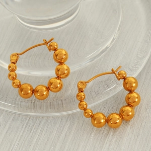 Minimalist gold beaded hoop earrings featuring a gradient design on white textured fabric