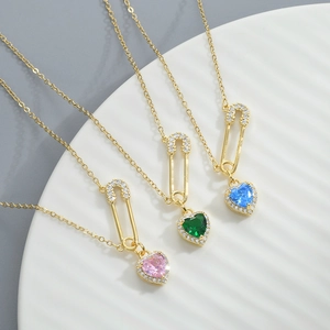 Detailed view of heart-shaped zircon pendants on gold-plated safety pin necklaces