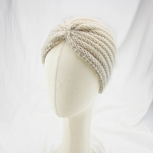 Detailed texture of beige knitted bohemian turban hat with twisted front design