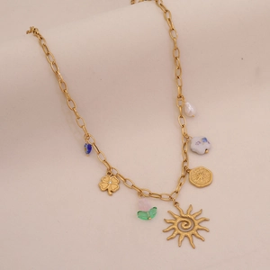 Close-up of golden necklace with sun, clover, flower charms and colorful beads