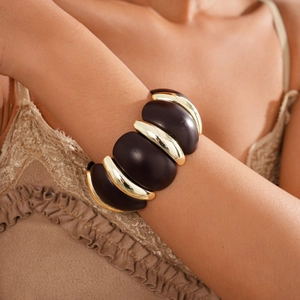 Detail shot of vintage acrylic round拼接 bracelet featuring gold metal links on wrist