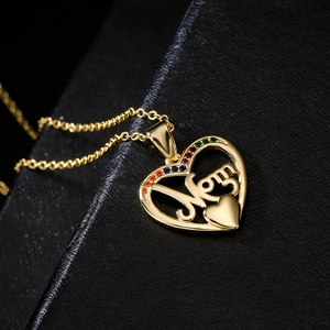 Gold MOM heart pendant necklace with colorful zircons on a black jewelry box