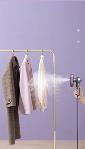 Handheld garment steamer releasing powerful steam to smooth out wrinkles on coats
