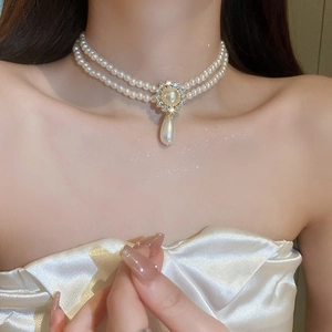 Détail d'un collier de perles double rang avec fleur en diamant et perle en goutte