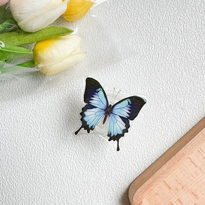 Detailed view of an insect-themed blue butterfly phone socket grip on a white surface
