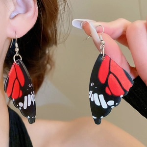 Detailed close-up of acrylic butterfly wing earrings with realistic red and black textures