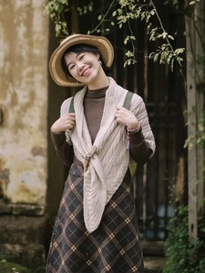 Detail of beige knitted shawl featuring fine texture and brown leather buckle