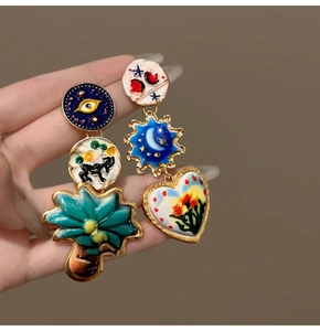 Detail of artistic asymmetric enamel earrings with colorful vintage patterns and charms