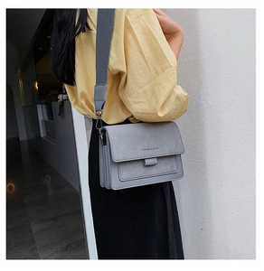 Detail view of the gray matte crossbody bag with its stylish wide fabric strap on a model