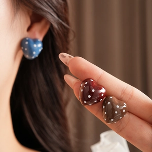 Detailed view of heart-shaped polka dot earrings in blue, red and brown colors