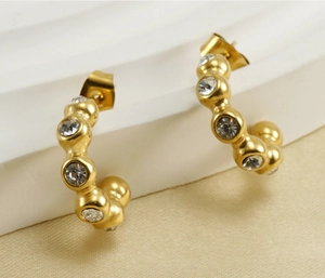Gros plan sur les boucles d'oreilles en U dorées 18K avec incrustations de zircone