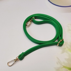 Vue détaillée de la bandoulière en cuir vert grainé avec boucles en métal doré réglables