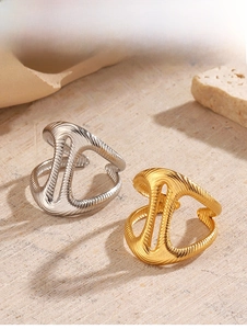 Detailed view of gold and silver irregular geometric rings on a textured stone surface
