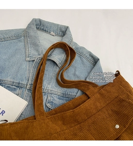 Detail of brown corduroy tote bag showing textured fabric and reinforced handle rivets
