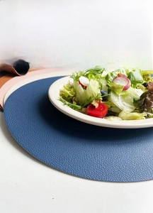Close-up of navy blue faux leather oval placemat with detailed pebble grain texture