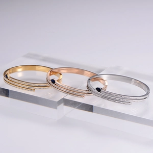 Macro detail of 18k gold-plated snake bracelets with zircon inlay and blue gemstones