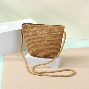 Detail of khaki woven straw shell bag showing its intricate texture and silver metal zipper