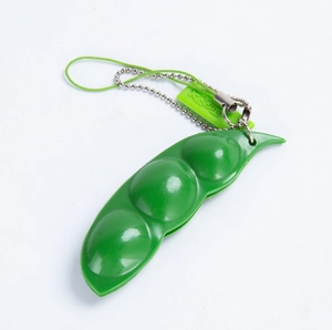 Close-up of green pea pod fidget toy with metal keychain and TORU brand tag