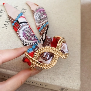Detailed close-up of golden infinity knot bracelet with colorful silk scarf ribbon