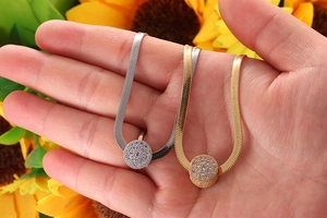 Detailed view of gold and silver snake chains with round sparkling diamond pendants
