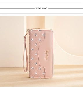 Detail of pink long wallet with embossed floral patterns and golden logo hardware