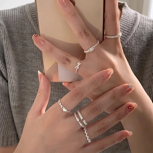 Minimalist silver twist stackable ring set with heart and bow designs on hand