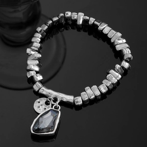Détail du bracelet en perles argentées avec cœur en cristal gris et breloque en métal