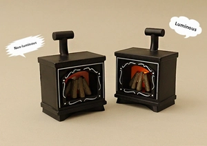 Close-up of miniature vintage black fireplace models with realistic glowing LED wood fire effect
